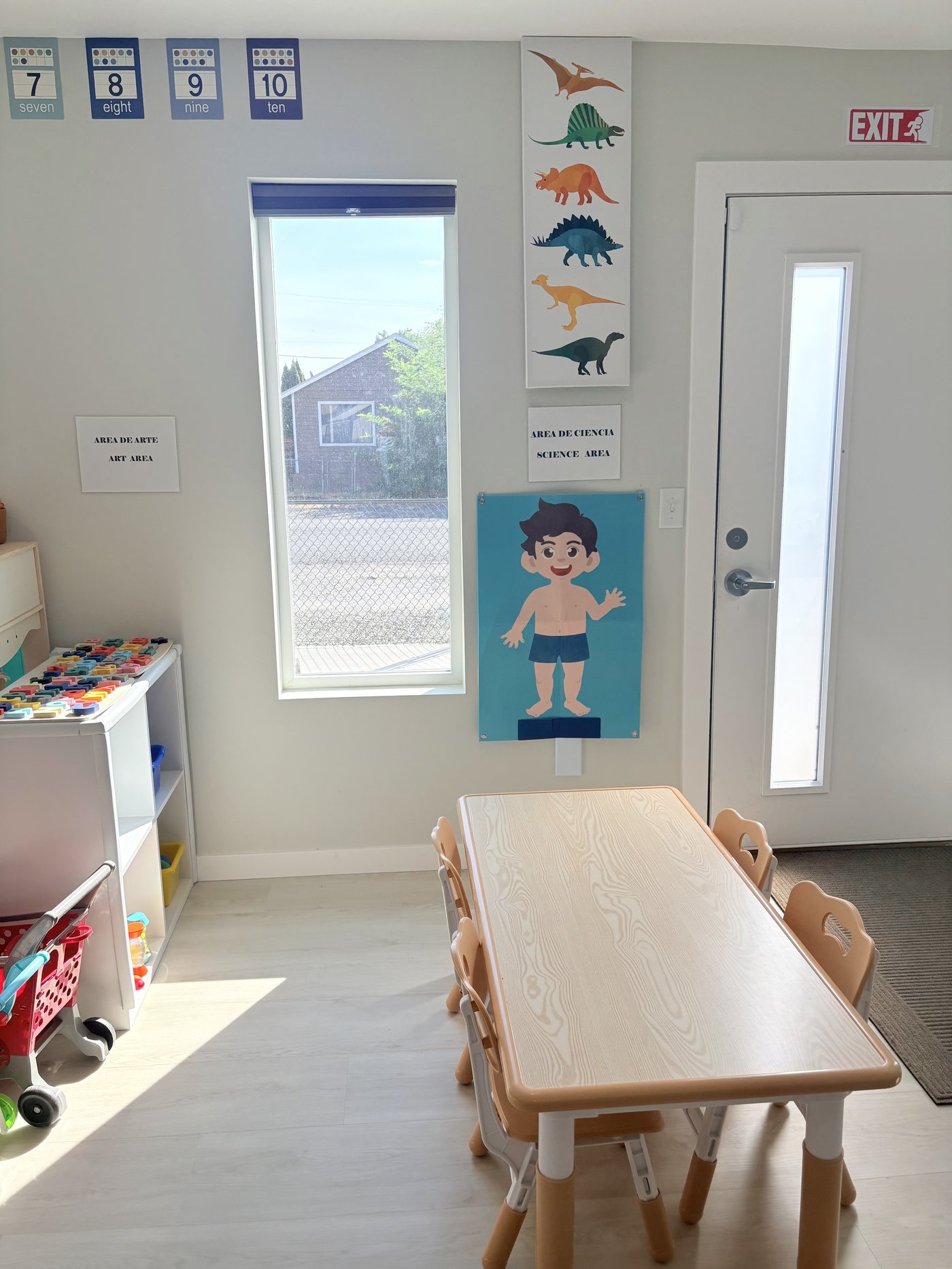 Art and science area with a child-height table, chairs and learning posters by the window