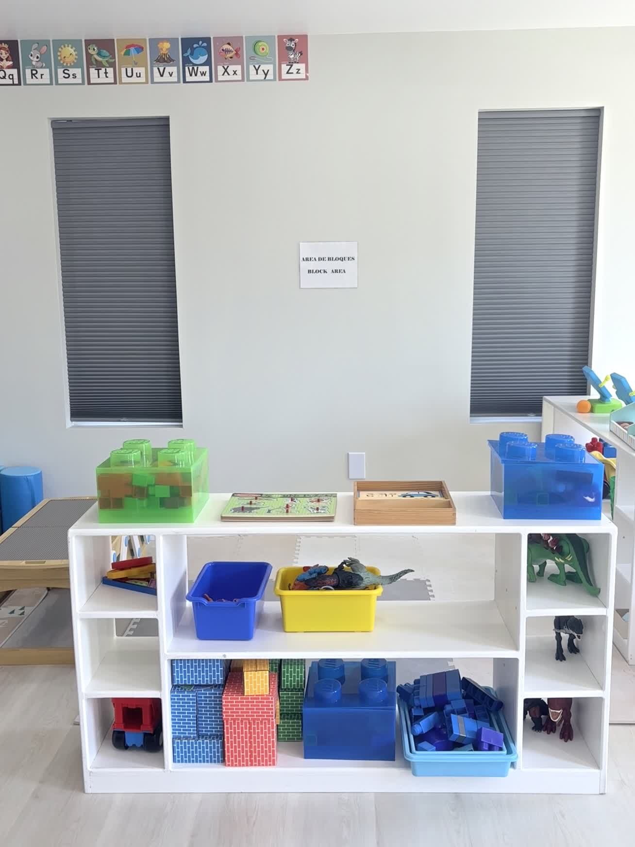Block area with labeled bins of building blocks, dinosaurs and a Lego play table