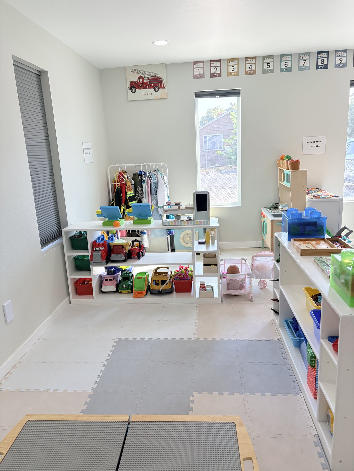 Dramatic play area with dress-up costumes, play kitchen and shelves of toy vehicles